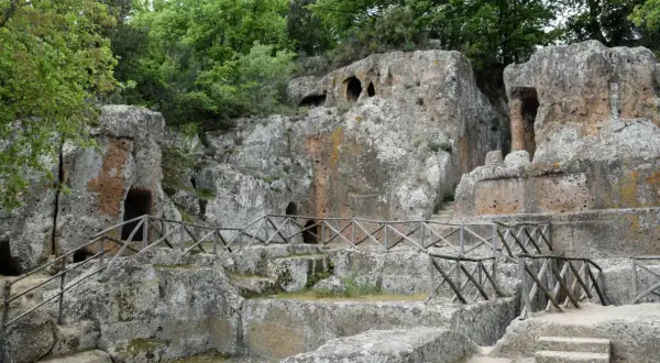 Antiche tombe etrusche scavate nella roccia, con sentieri e recinzioni in legno. Un suggestivo scorcio della mappa dei siti etruschi in Toscana.