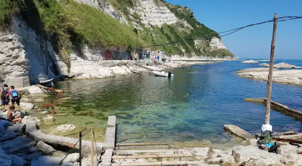 La spiaggia della Scalaccia, con le sue acque cristalline e le scogliere bianche, accoglie bagnanti e piccole imbarcazioni.