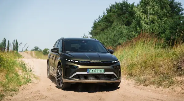 Zielona Skoda Enyaq na piaszczystej drodze, testowana pod kątem zasięgu.