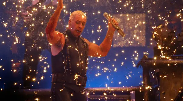 Till Lindemann z Rammstein śpiewa na koncercie, otoczony fajerwerkami.