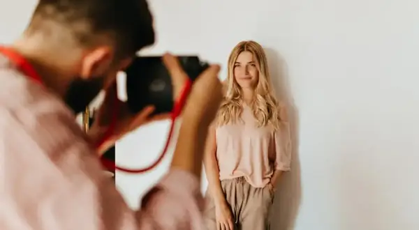 Fotograf robi zdjęcie uśmiechniętej blondynce. Zastanawiasz się, ile kosztuje sesja zdjęciowa?