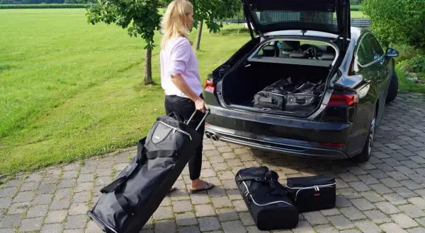 Frau packt Gepäck für den Roadtrip. Koffer und Taschen werden in den Kofferraum geladen.