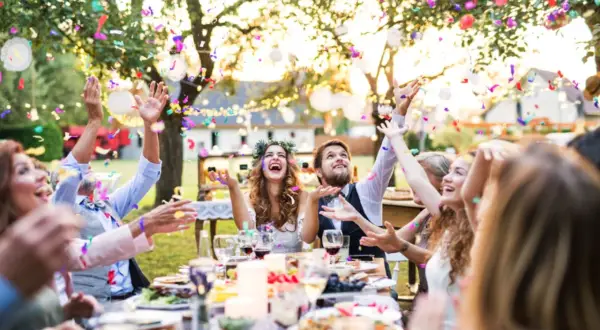 Fröhliche Gäste werfen Konfetti bei einer Gartenparty. Tolle **Gartenparty Ideen** für unvergessliche Momente mit Freunden und Familie.