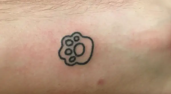 Małe tatuaże męskie: czarna łapka zwierzęcia na skórze, symbol przyjaźni i lojalności.