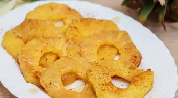 Rodajas de piña a la plancha, doradas y jugosas, espolvoreadas con canela. Un postre tropical irresistible.