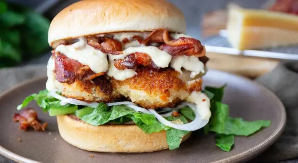 En saftig kycklingburgare med krispigt bacon, sallad, lök och en krämig dressing. Perfekt för ett gott hamburgerdressing recept.