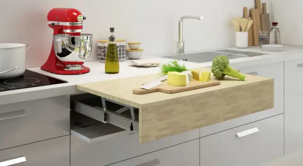 Un piano estraibile sul tavolo della cucina con formaggio, broccoli e un coltello su un tagliere.