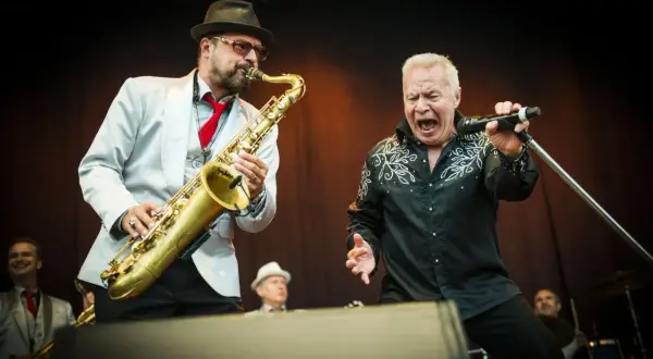 Stellan Sundahl sjunger med full kraft medan en saxofonist ackompanjerar.