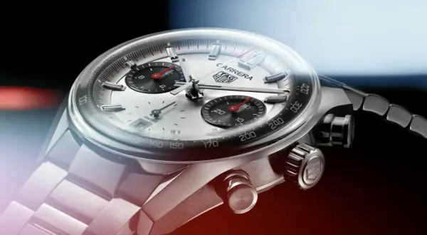 Primer plano de un reloj TAG Heuer Carrera. El cristal mineral se raya levemente, mostrando la esfera plateada y los sub-diales negros.