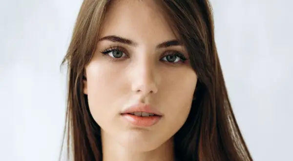 Delikatna, soft girl z zielonymi oczami i brązowymi włosami, patrzy prosto w obiektyw.