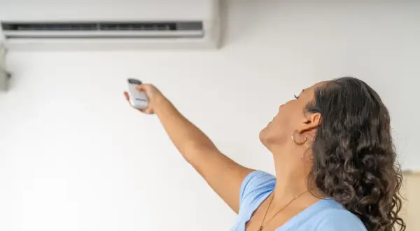 Donna con telecomando regola il condizionatore dal design elegante. La canalina è quasi invisibile, integrata perfettamente.