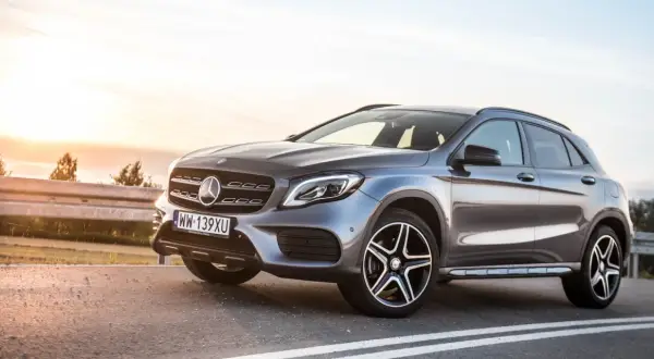 Szary Mercedes GLA 220 z polskimi tablicami rejestracyjnymi stoi na poboczu drogi o zachodzie słońca.