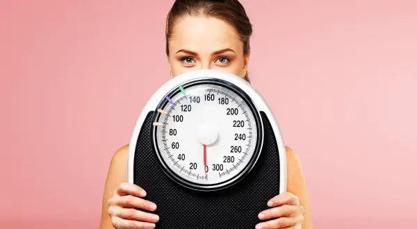 Donna con bilancia, un simbolo per la dieta 1500 calorie e il controllo del peso.