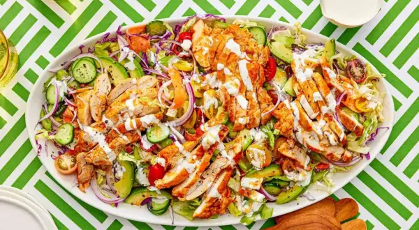 En stor kyckling sallad med avokado, tomat, gurka och rödlök, toppad med en krämig dressing. Perfekt för en lätt lunch.