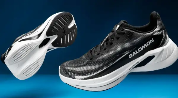 Deux chaussures de course Salomon Spectur noires et blanches, avec semelles blanches et noires, sur fond bleu.