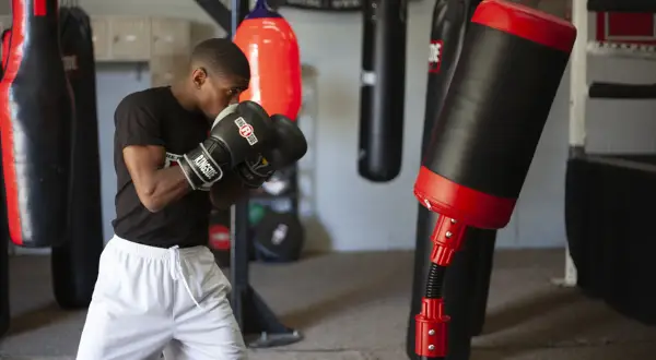 A boxer practices boxing drills in a gym, surrounded by various punching bags.