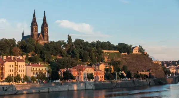 Wyszehrad góruje nad Wełtawą, z dominującą bazyliką i zielonymi wzgórzami.