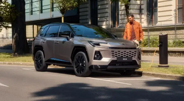 Nowy Toyota RAV4 2025 cena: stylowy SUV ładowany przy miejskiej stacji.