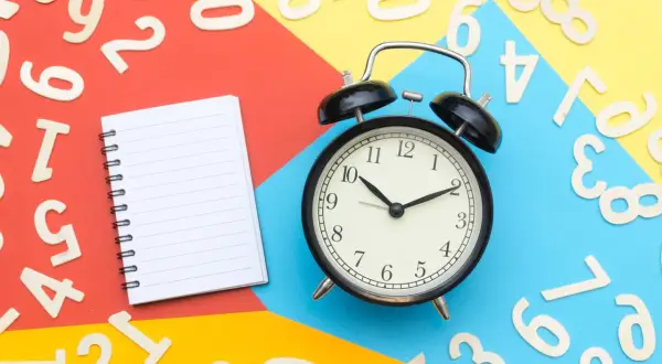 Sulla scrivania, numeri sparsi, un quaderno e una sveglia indicano che si può cambiare assicurazione prima della scadenza annuale.