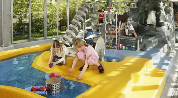 Kinder spielen im Wasserbereich des vier Jahreszeiten Parks Oelde mit bunten Bällen und Wasserrädern.