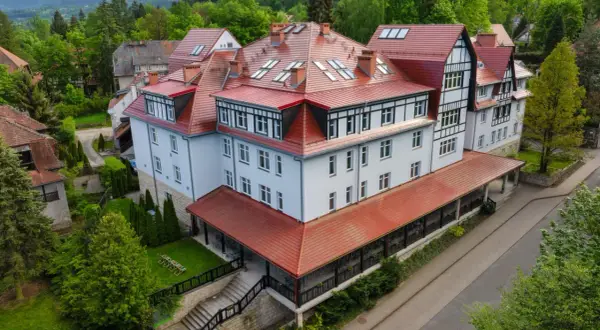 Polanica Zdrój Medical Sensus – okazały budynek z czerwoną, wielospadową dachem, otoczony zielenią.