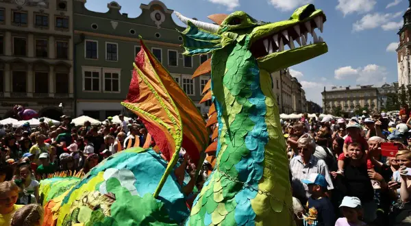 Kolorowy smok na krakowskim Rynku Głównym podczas Parady Smoków. Tłumy widzów podziwiają widowiskową postać.