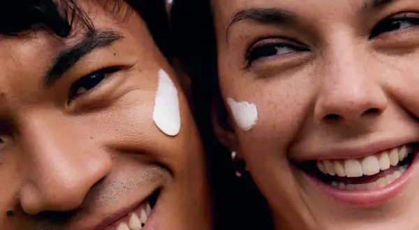 Coppia sorridente con crema sul viso, godendo dei benefici del vapore viso per una pelle radiosa.