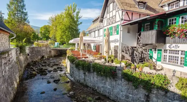 Urokliwy deptak w Szklarskiej Porębie nad górskim potokiem. Restauracja z ogródkiem i zielonymi okiennicami.