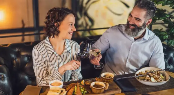 Para celebruje w najdroższej restauracji w Warszawie. Wznoszą toast winem, delektując się wykwintnym jedzeniem.