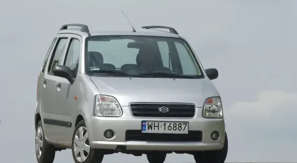 Srebrny Suzuki Wagon R+ z polskimi tablicami rejestracyjnymi WH 16887, zaparkowany na tle jasnego nieba.