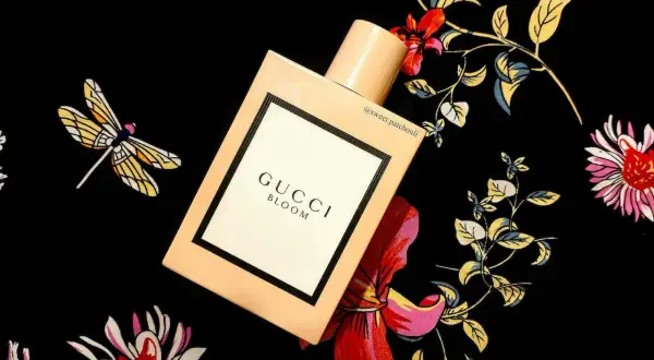 Elegancki flakon Gucci Bloom 100ml na tle kwiecistego wzoru z ważkami.