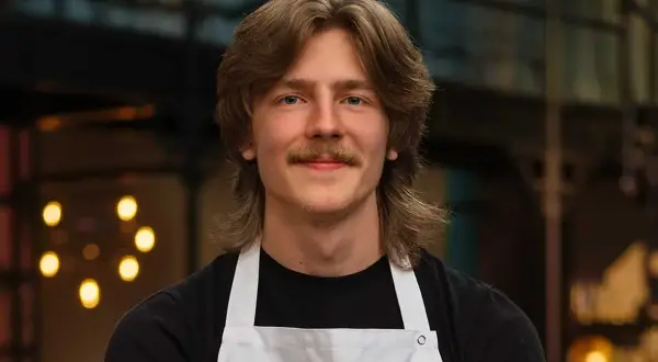 Jacob Jansson, en ung man med mustasch och långt hår, bär en vit kockförkläde.