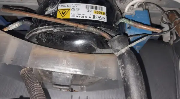 Lodówka Whirlpool nie chłodzi, ale zamrażarka działa. Widoczny kompresor z etykietą R600A.