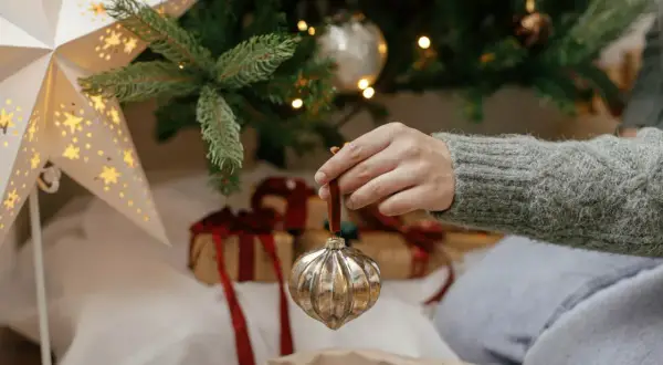 Ręka zdejmuje ozdobę z choinki. Czas pomyśleć, kiedy zdjąć ozdoby świąteczne.