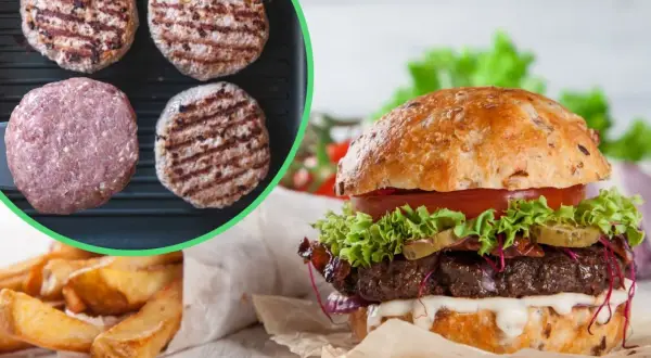 Gotowe burgery i surowe mięso na patelni grillowej, obok gotowy burger i frytki.
