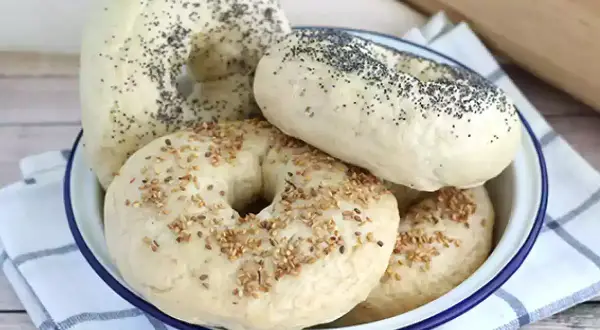 Färska bagels med vallmofrön och sesamfrön i en skål, redo för ett gott bagels recept.