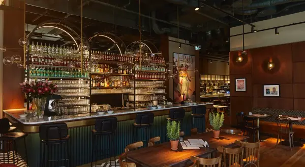Elegancki bar z mnóstwem butelek alkoholu i kieliszków, idealne miejsce na odkrywanie ciekawych restauracji w Warszawie.