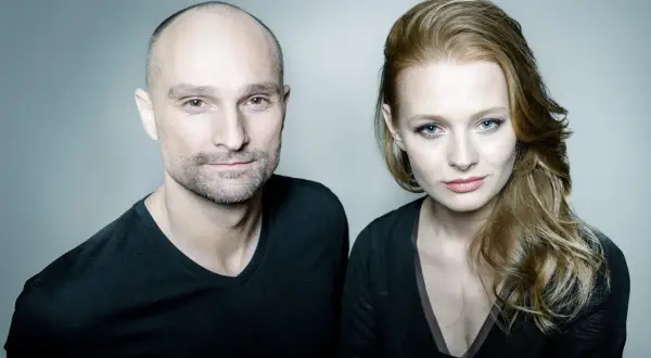 Dominik Strzelec i jego żona, uśmiechnięci, patrzą w obiektyw.