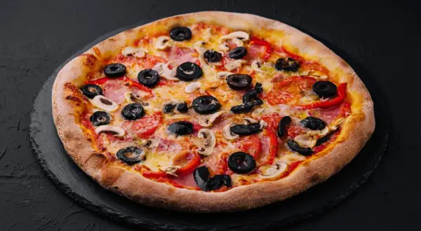 Chrupiąca pizza z oliwkami, pieczarkami i papryką na czarnym tle.