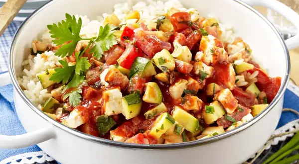 Eine köstliche zucchini-reis-pfanne einfach zubereitet mit viel Gemüse und Hähnchen. Frisch garniert mit Petersilie.