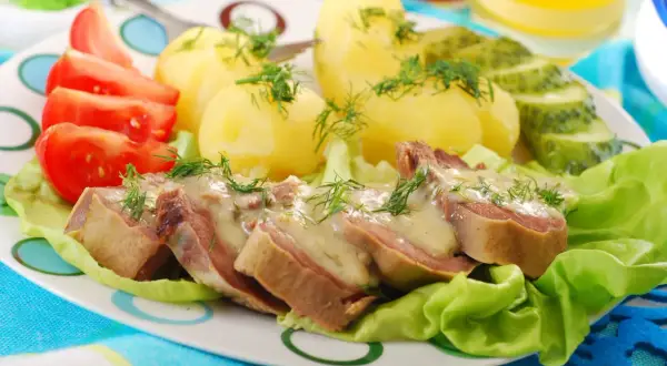 Pyszne ozorki w sosie chrzanowym z ziemniakami, pomidorami i ogórkiem kiszonym.
