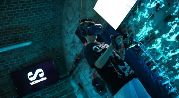 Chłopak w goglach VR w Krakowie, zanurzony w wirtualnej rzeczywistości. Na ekranie logo VRStudio.