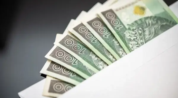 Banknoty 100 zł w kopercie. Symbol jawności wynagrodzeń i transparentności finansowej.