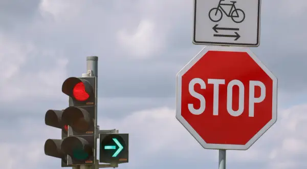 Ampel zeigt Rot, daneben ein Stoppschild. Wie lange halten? Radweg-Schild darüber.