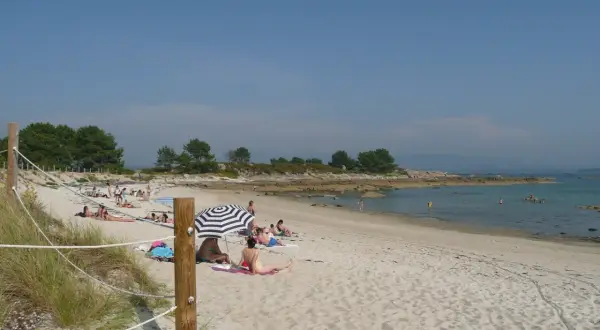 Gente disfrutando del sol en unas tranquilas playas nudistas Galicia, con arena dorada y aguas cristalinas.