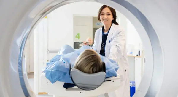 Lekarka uśmiecha się do pacjentki leżącej na stole do rezonansu. Skierowanie na rezonans jest ważne dla diagnostyki.