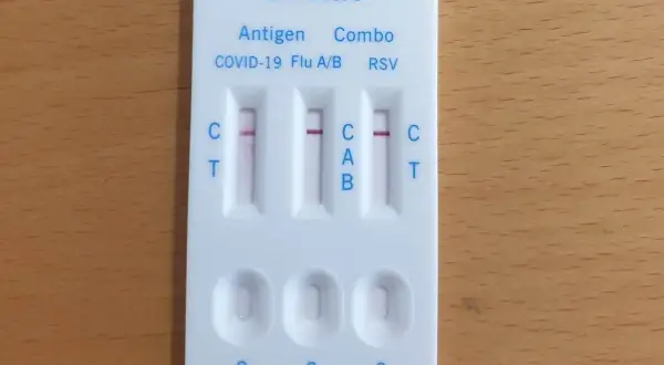 Test combo z widocznymi dwoma czerwonymi paskami, wskazującymi na pozytywny wynik testu na COVID-19 i grypę.