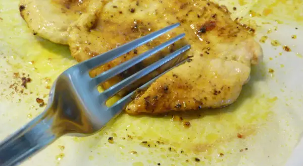 Un succulento petto di pollo in padella morbido, dorato e speziato, pronto per essere gustato con una forchetta.