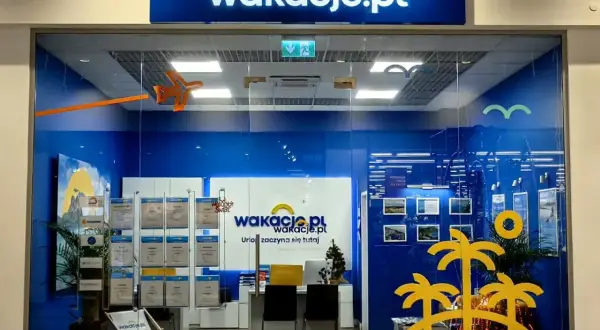 Witryna biura podróży Wakacje.pl z logo, wystawami ofert i dekoracjami wakacyjnymi.