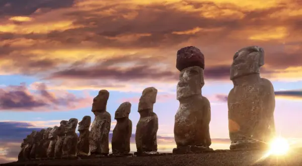 Kamienne posągi Moai na Wyspie Wielkanocnej o zachodzie słońca.